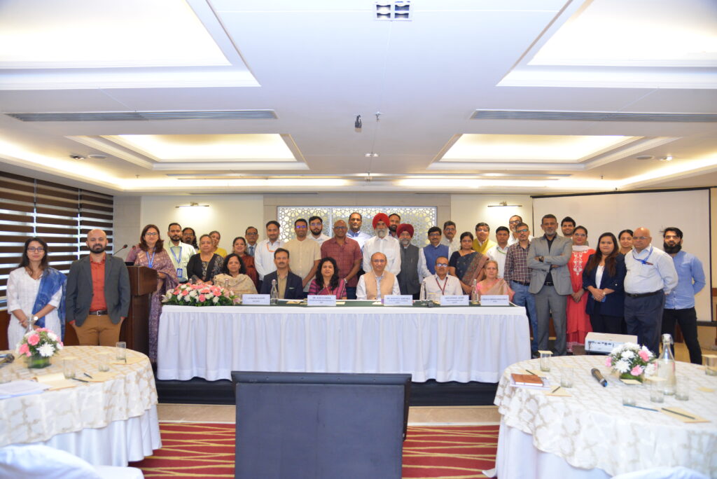 A large group of people convenes in a decorated conference hall for the Regulatory Conclave on Smart Protein with six panelists prominently featured.